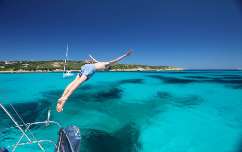 Jumping into the crystal clear waters of Cala Santa Maria, Sardinia, Italy